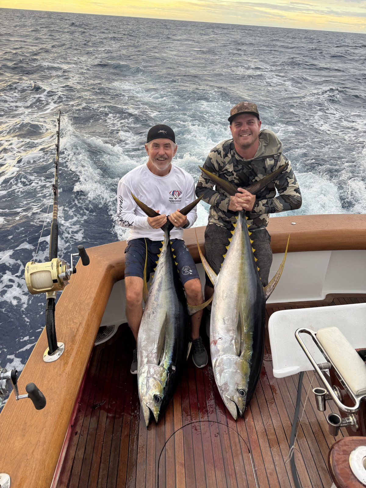 Two anglers with a pair of yellowfin ahi on the teak deck