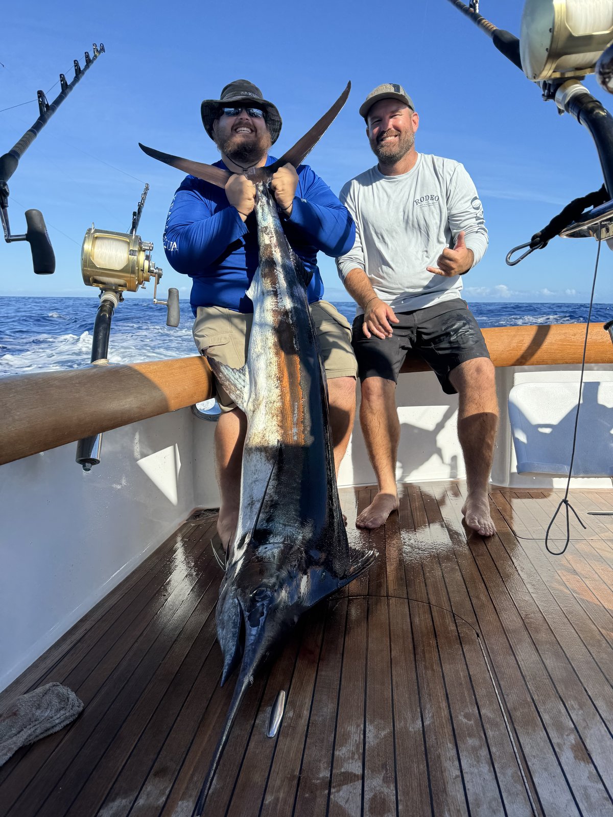 Two anglers with a marlin on the teak deck